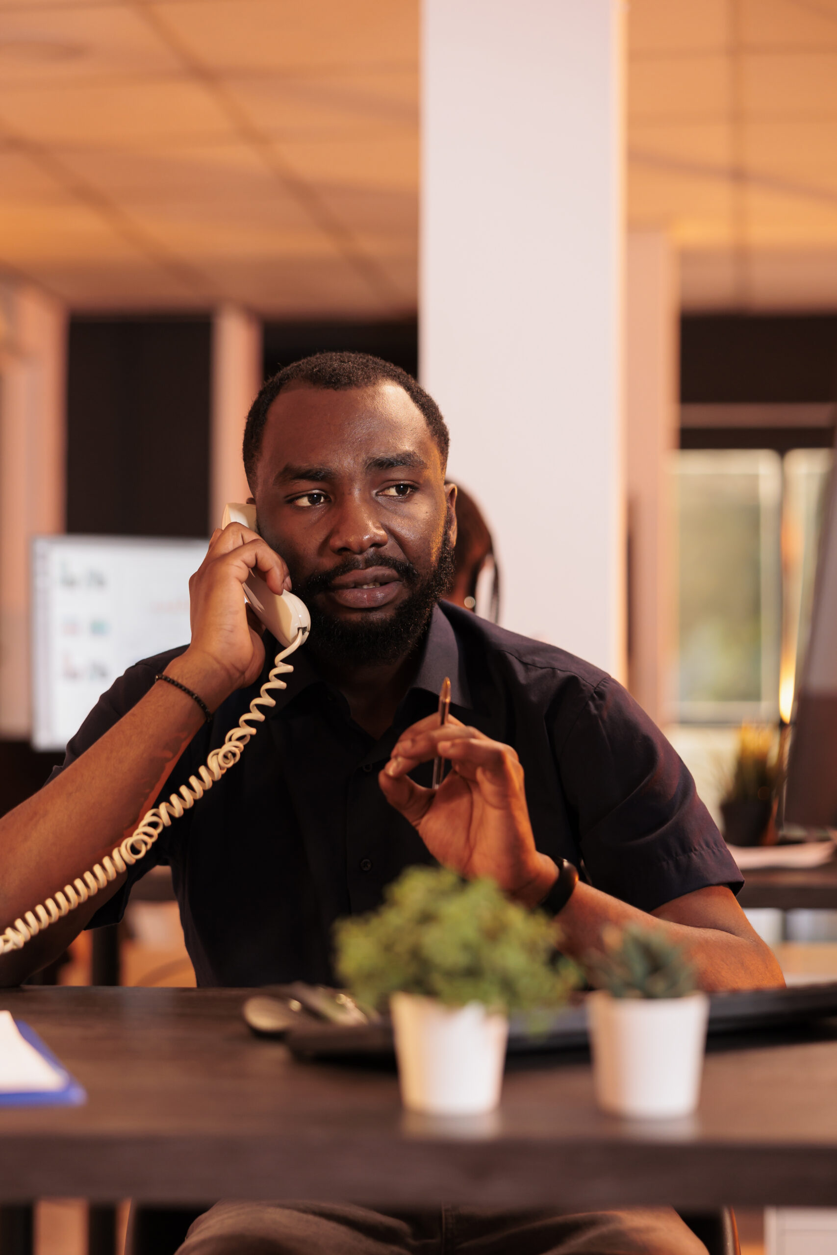 Male freelancer talking to people on landline phone, answering call to discuss about research information for report presentation. Chatting on office telephone line to do company paperwork.